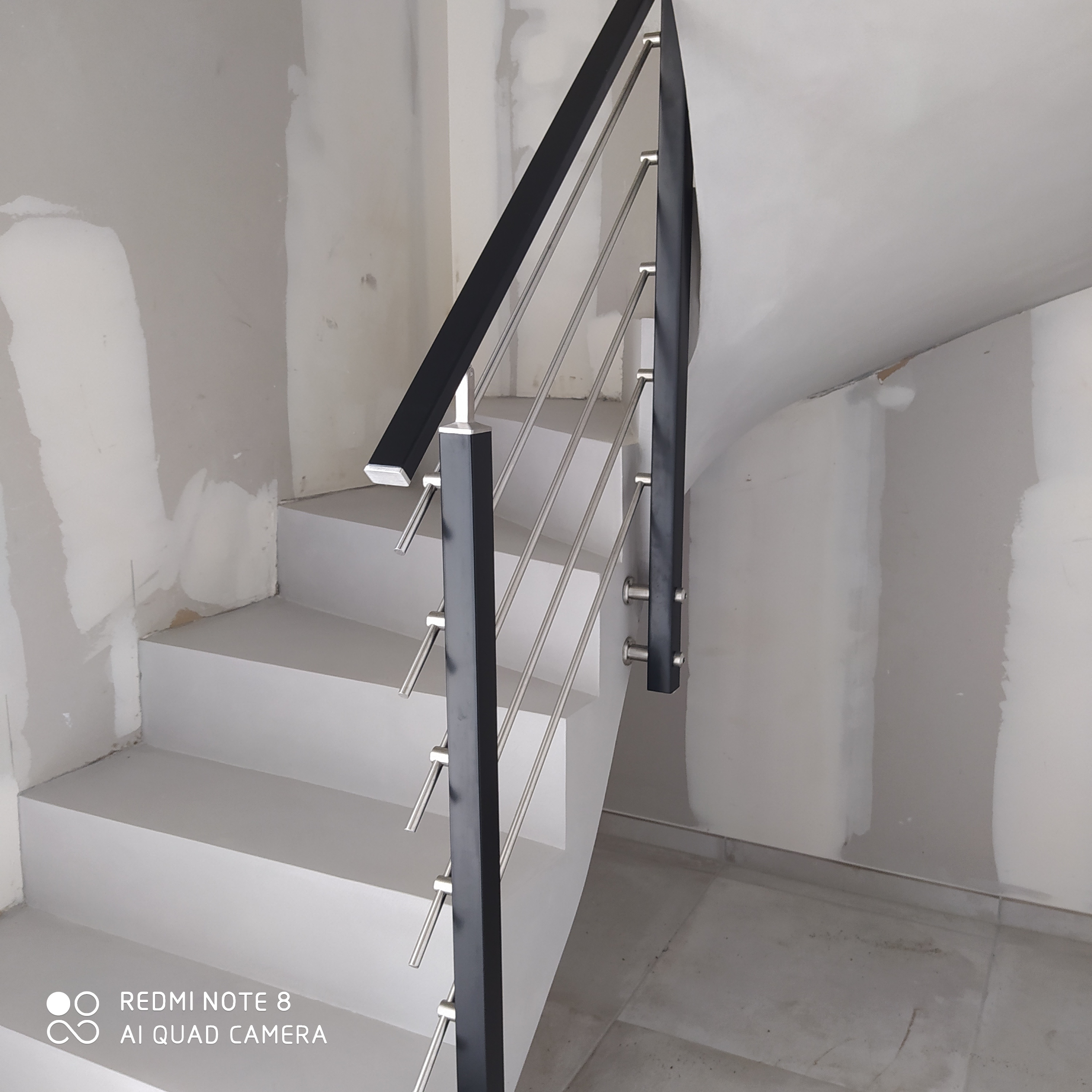Garde corps en inox sur un escalier à paillasse décoré en béton ciré