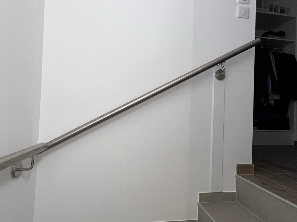 Main courante avec accessoires tout inox, le long d'un mur. Matière résistante à la chaleur et aux variations de température.