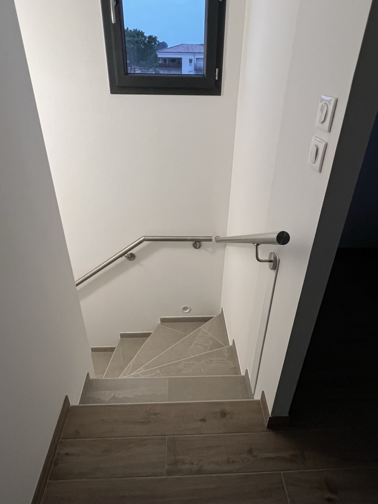 Main courante inox sur un escalier, dans une maison individuelle, près de Calvisson et Sommières, en région Occitanie.