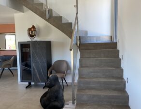 Modèle original d'une balustrade en verre, avec poteaux carrés et main courante en inox, posée sur un escalier à paillasse, en Belgique près de Lille et Calais.