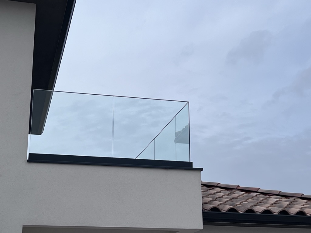 Pose soigneuse d'un verre feuilleté trempé de 13mm sur un muret extérieur.