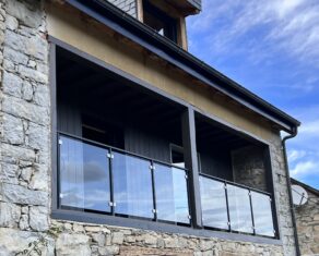 Maison au charme rustique, située dans la pittoresque région d'Occitanie, dévoile un balcon accueillant orné d'une magnifique balustrade en verre d'un mètre de hauteur.