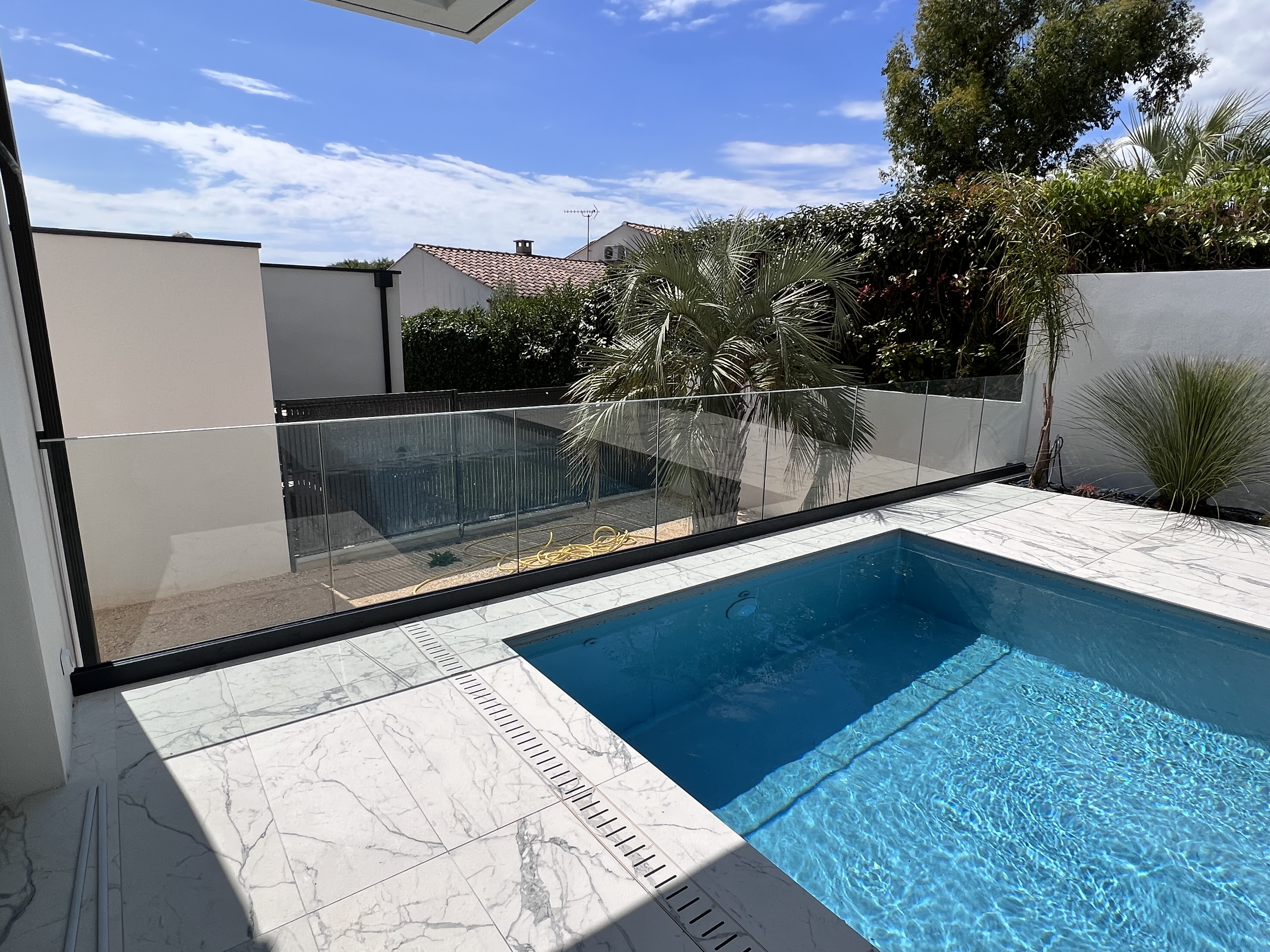 Rambarde en verre et aluminium d'un mètre de hauteur, installée à l'extérieur d'une maison individuelle, en région Occitanie.