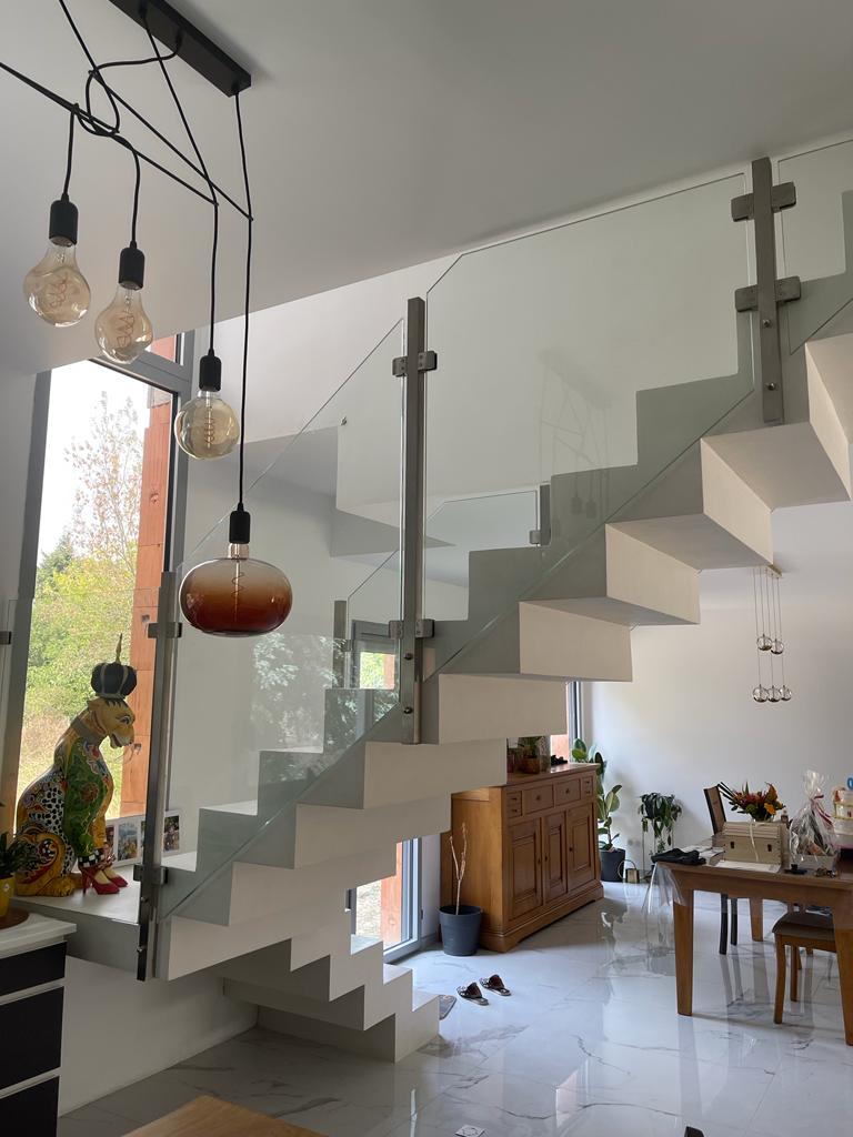 Garde-corps en verre plein, en verre trempé et en inox, installé sur un escalier en béton ciré.